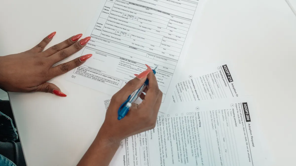 hands filling out a paper form with a pen