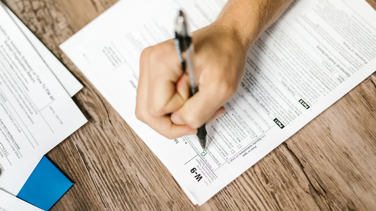 hand completing a form on a desk