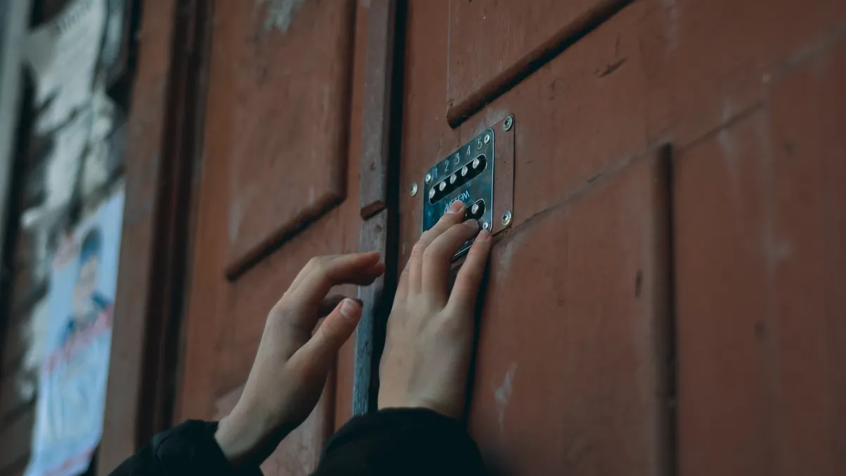 hands entering a code on a door keypad