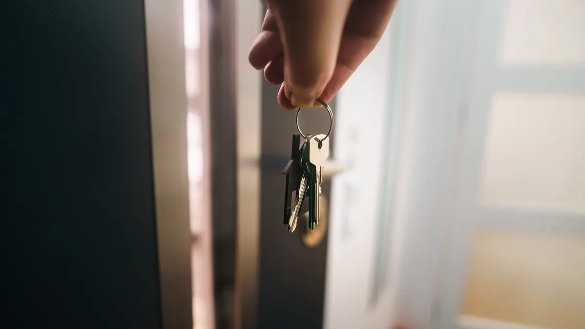 hand holding house keys at a doorway